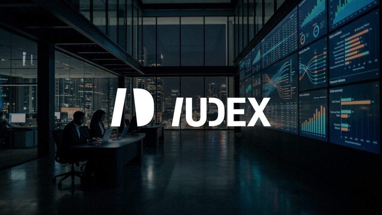 Oficina con pantallas de gráficas de cobranza y un equipo reunido, con el logotipo de IUDEX