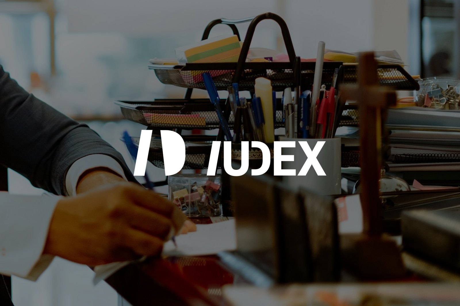 Un abogado escribe en su escritorio, con el logotipo de IUDEX sobre la imagen